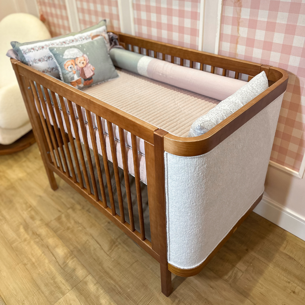 Berço de Madeira em um quarto de menina com papel de parede xadrez rosa.