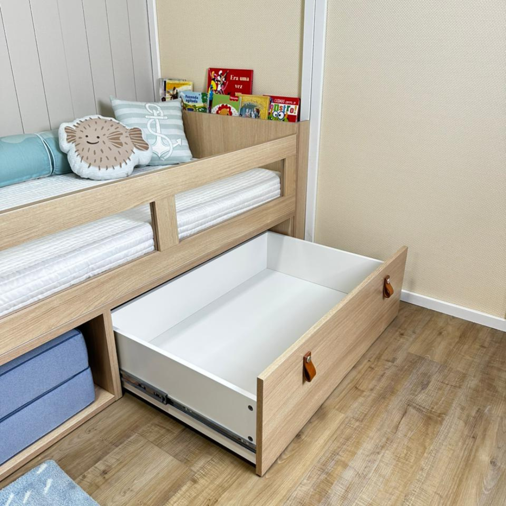 A gaveta inferior é funcional? Sim, a cama inclui uma gaveta com puxador em alça de couro ecológico, ideal para organizar brinquedos ou roupas de cama, otimizando o espaço do quarto.