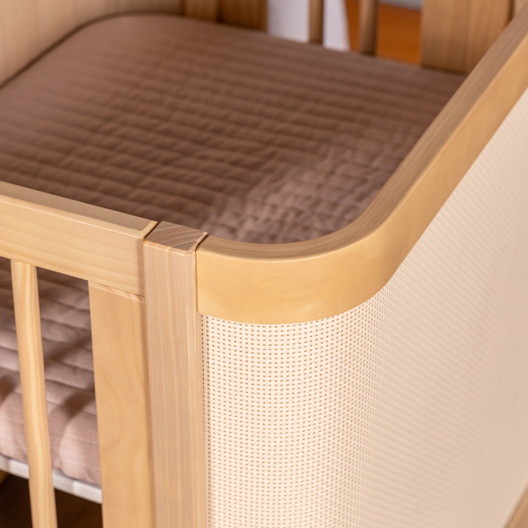 Cantos arredondados, grades palito e tela Rattan, todo charme do mini berço Paglia.